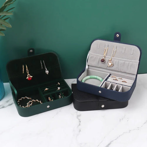 Deux coffrets à bijoux ouverts, vert et bleu, avec leurs compartiments de rangement.